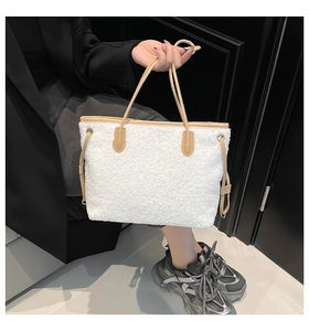 Close-up of white plush tote bag with beige leather trim and drawstring details