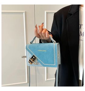 Detail of light blue crossbody bag with white stitching and gold FASHION & BAGS logo