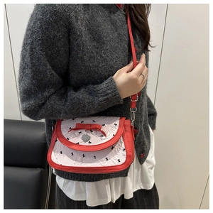 Détail du sac bandoulière en cuir rouge avec tissu plissé crème et breloque cœur
