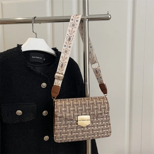 Brown checkered woven underarm bag with ethnic print strap on a display hanger