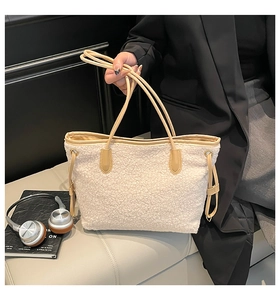 Detail of white plush tote bag featuring khaki leather handles and side drawstring accents