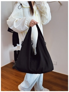 Detailed side view of large black tote bag with adjustable drawstrings and metal buckles