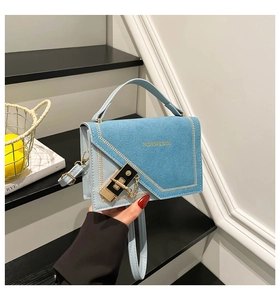 Detail of light blue crossbody bag featuring mixed textures and white chevron stitching