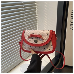 Détail du nœud rouge et du pendentif cœur sur le sac à bandoulière texturé blanc