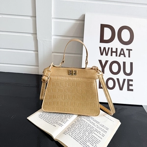 Bolso Kelly dorado con textura de cocodrilo sobre libro, estilo retro francés chic