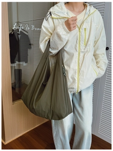 Detailed close-up of dark olive green nylon tote bag with functional side zipper texture