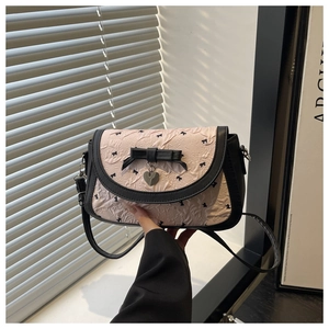 Détail du tissu plissé rose avec nœud en cuir noir et breloque en forme de cœur