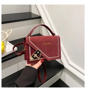 Detail of wine red handbag with gold buckle and V-shaped leather patchwork design