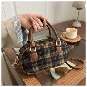 Classic brown plaid bowling bag with leather trim held in a warm lifestyle setting