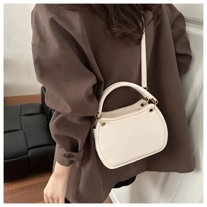 Detail view of cream white crescent bag with gold metal eyelets and adjustable strap