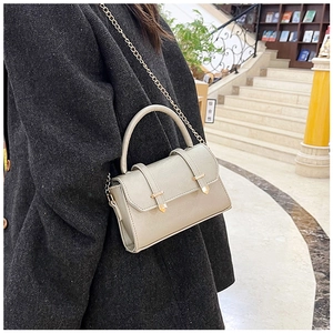 Detail of beige leather crossbody bag with gold chain and handle on tweed coat