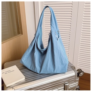 Detail of blue textured nylon tote bag featuring a decorative zipper and knot puller
