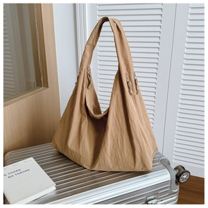 Detail of caramel tote bag with side zipper on silver luggage in casual setting