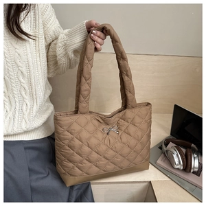 Close-up of khaki quilted tote bag with diamond stitching and metal bow detail