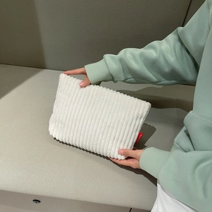 Detailed close-up of white corduroy envelope clutch bag with soft ribbed texture and side label