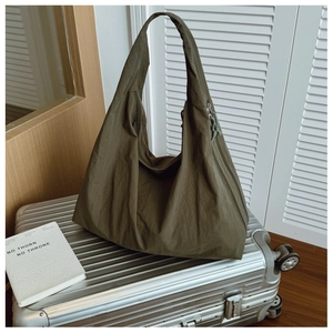 Olive green large hobo tote bag resting on a silver suitcase in a travel scene