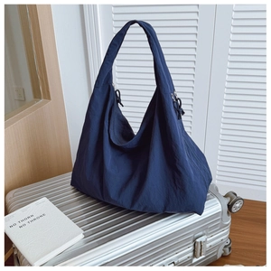 Detail view of large capacity navy blue tote bag on a silver suitcase for travel