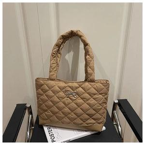 Detail of khaki quilted tote bag with silver bow accent and soft padded handle textures