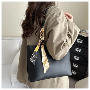 Detail of black leather tote bag featuring white stitching and baroque print silk scarf