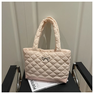 Close-up of quilted peach pink tote bag with metal bow buckle and diamond stitching