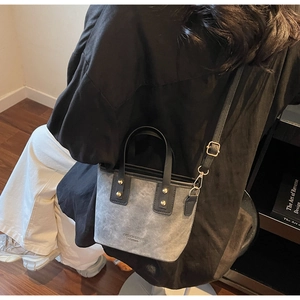 Detail of grey crossbody bucket bag showing adjustable strap and fashion leather text