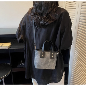 Detail of vintage grey bucket bag with golden rivets and dual straps shown on a model