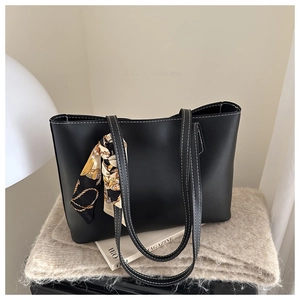 Detail of black tote bag with white contrast stitching and patterned silk scarf accent