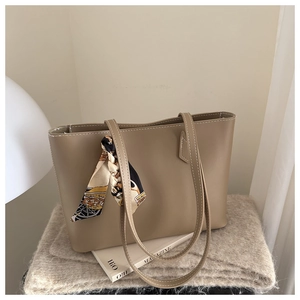 Detail of earthy tone leather tote bag featuring decorative silk scarf and long straps