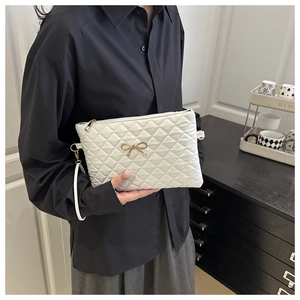 Détail du sac à bandoulière matelassé blanc avec nœud doré et fermeture éclair