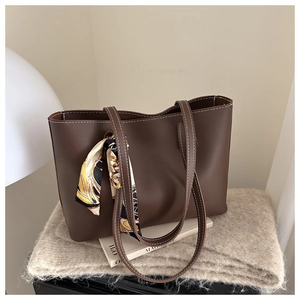 Close-up of brown leather tote bag with contrast stitching and decorative silk scarf