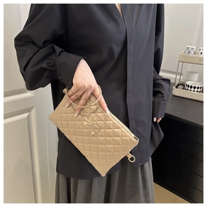 Détail d'un sac matelassé beige avec fermoir nœud doré et poignée ronde en métal