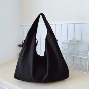 Minimalist black oversized tote bag with nylon texture on white marble surface