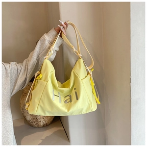 Détail du sac cabas en toile jaune clair avec lettrage Hai et décorations en ruban