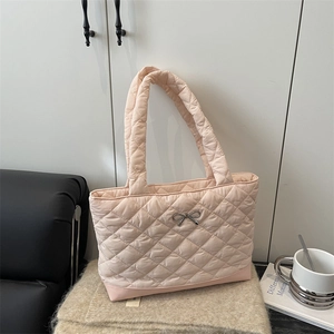 Pink quilted tote bag with silver bow accent on a stylish minimalist background