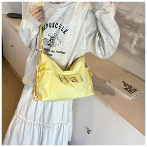 Détail du sac bandoulière en nylon jaune vif avec inscription 'Hai' et sangle réglable