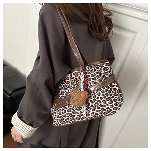 Close-up of leopard print suede tote with brown leather straps and plush bear charm
