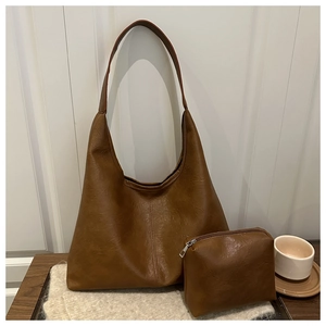 Detail of soft brown faux leather hobo bag with matching zipper pouch on wood table