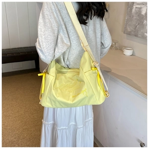 Détail d'un sac bandoulière en nylon jaune pâle avec broderie et détails de nœuds
