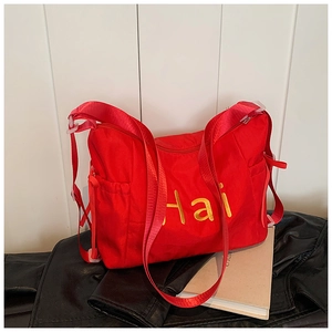 Détail du grand sac cabas rouge en nylon avec broderie Hai jaune et bandoulière réglable