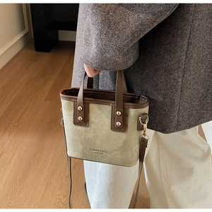 Sage green canvas bucket bag with leather trim and shoulder strap worn by a model