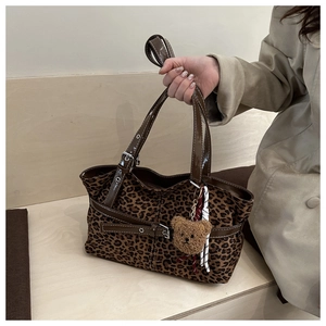 Detail view of leopard print tote bag with brown handles and cute plush bear charm