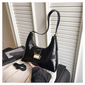 Close-up of black glossy hobo bag with metal buckle and adjustable shoulder strap