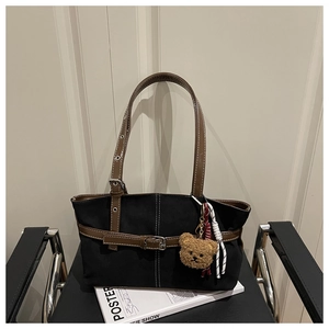 Dettaglio della borsa tote minimalista in nero e marrone con ciondolo a forma di orsetto