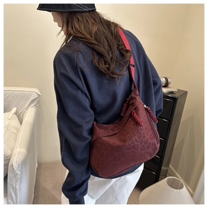 Détail du sac bandoulière bordeaux imprimé léopard avec tirette de zip tissée rouge vif