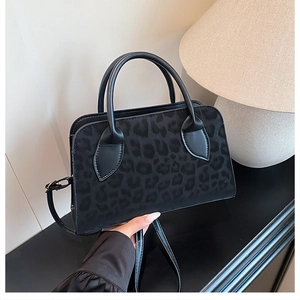 Close-up of black matte leopard texture tote bag with dual handles and leather strap