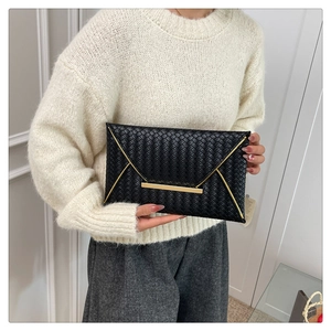 Detailansicht der schwarzen geflochtenen Umschlagtasche mit elegantem goldenem Metallriegel