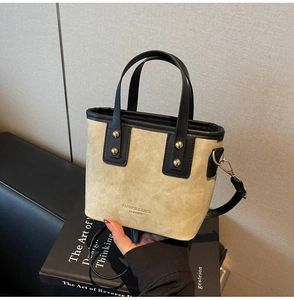 Detail of minimalist bucket bag with gold rivets and black leather handles