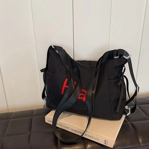 Black canvas tote bag with red Ha embroidery and adjustable strap on a white background