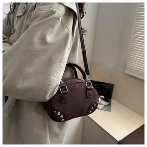 Detail of dark brown suede shoulder bag with metallic studs and fine leather strap