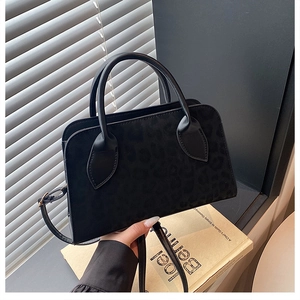 Close-up of black leopard print matte tote bag with round handles and gold buckles